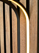 Warm white BLAQ Aura LED strip illuminated along curved slat wall against wood panels